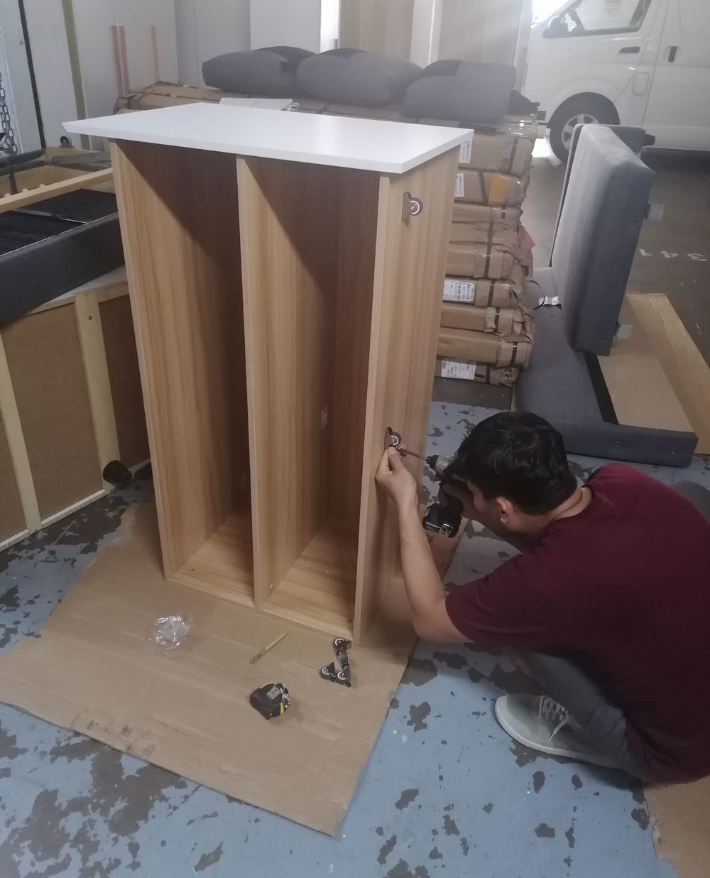 A JustGo team member assembling a wooden cabinet